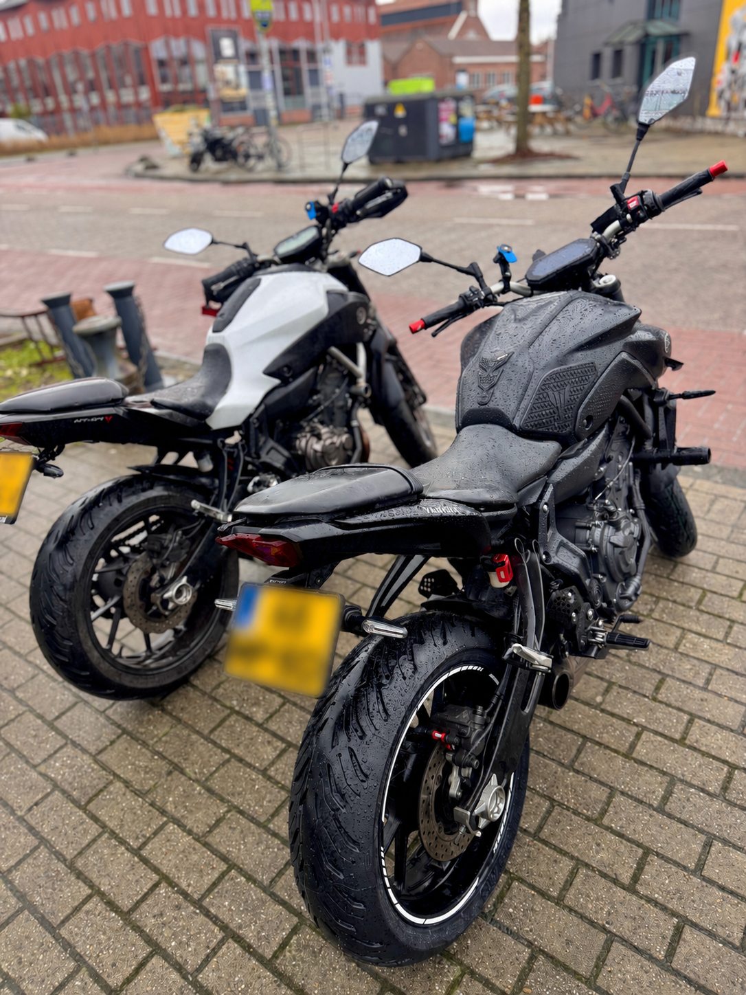 Two motorcycles parked together in rainy city conditions during a group ride