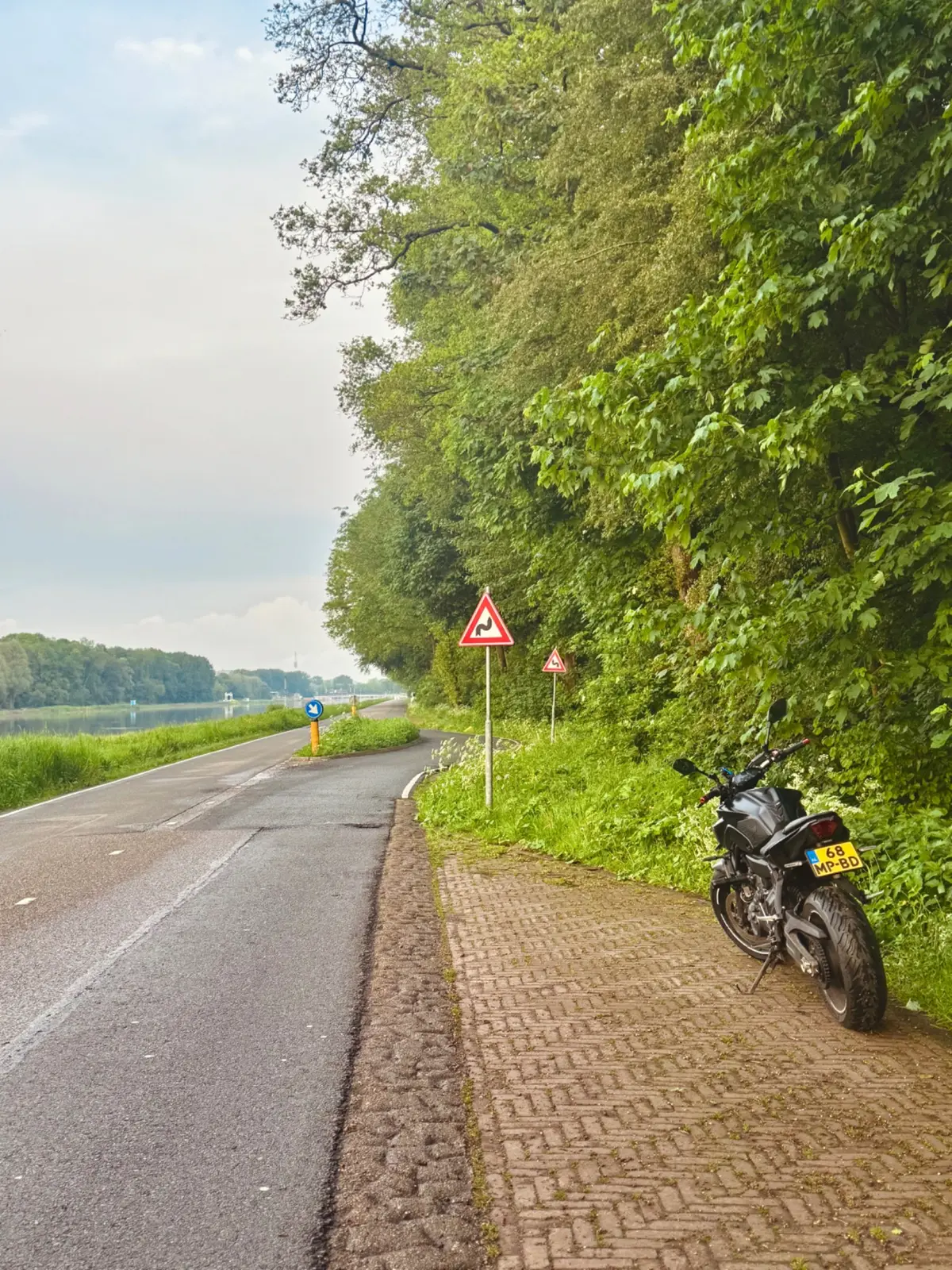 Yamaha MT-07 parked near a curvy road sign beside a riverside road