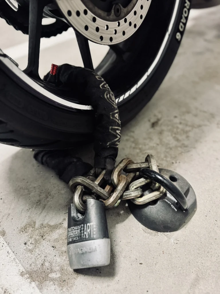 Close-up of a heavy motorcycle chain lock and padlock used for parking security