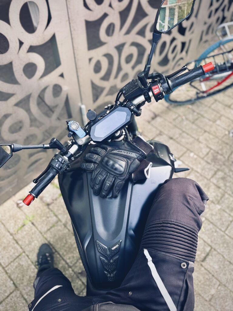 Rider wearing motorcycle pants and boots with gloves placed on a Yamaha MT-07 tank before a ride.
