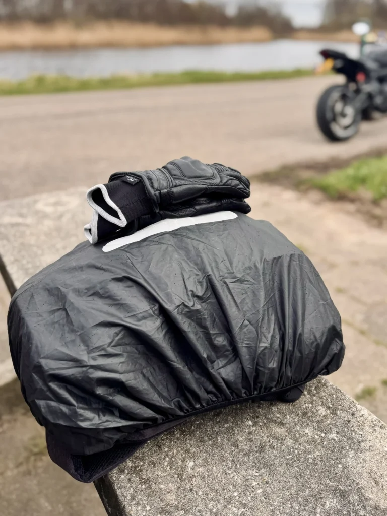 Motorcycle riding backpack with rain cover placed near a riverside road