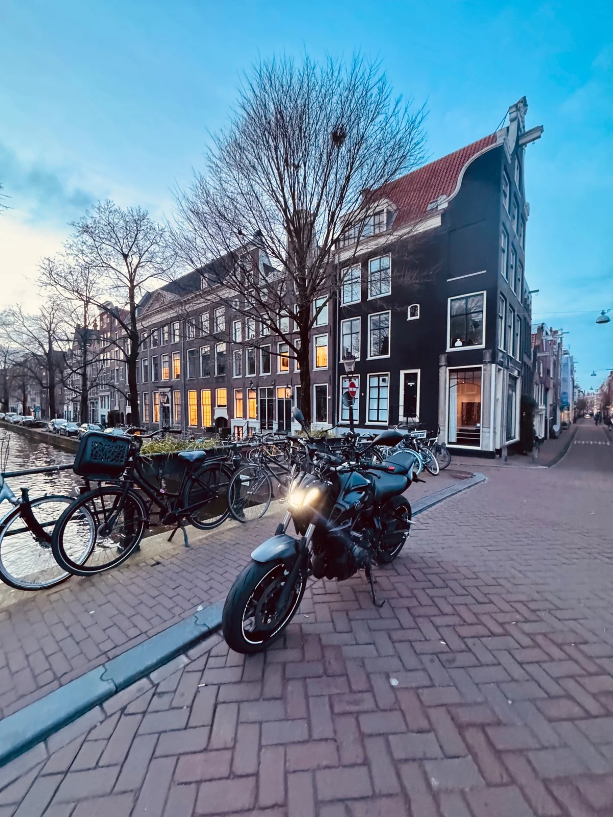 Black Yamaha MT-07 parked beside an Amsterdam canal at dusk