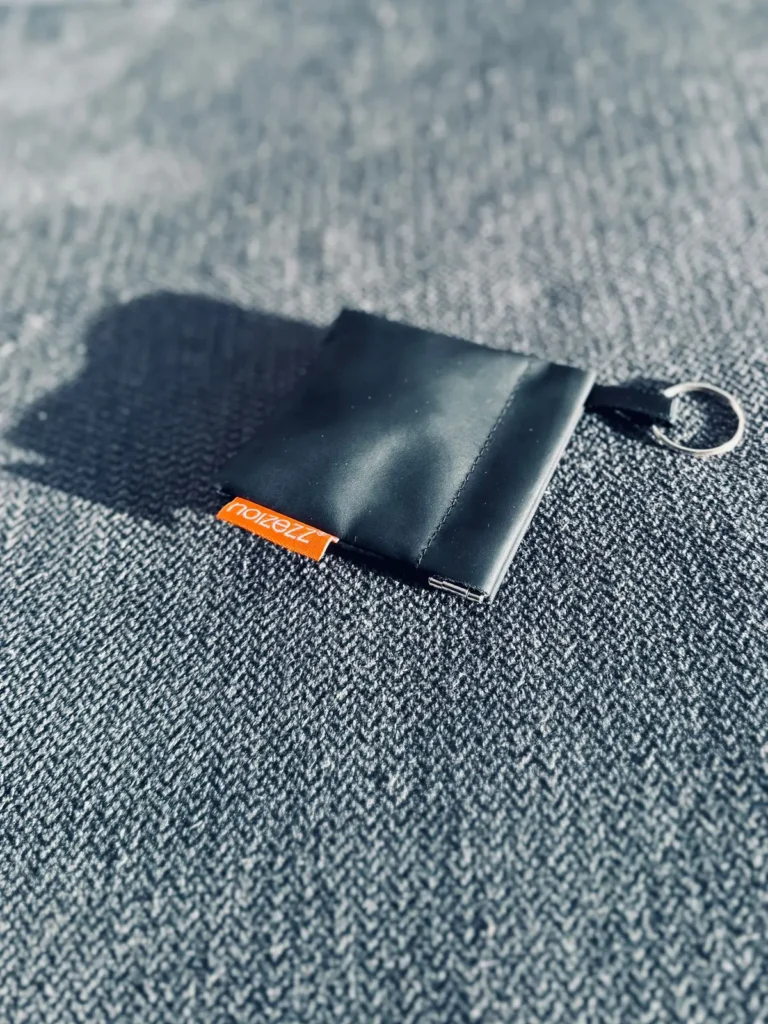 Noizezz motorcycle earplugs placed on a textured grey carpet