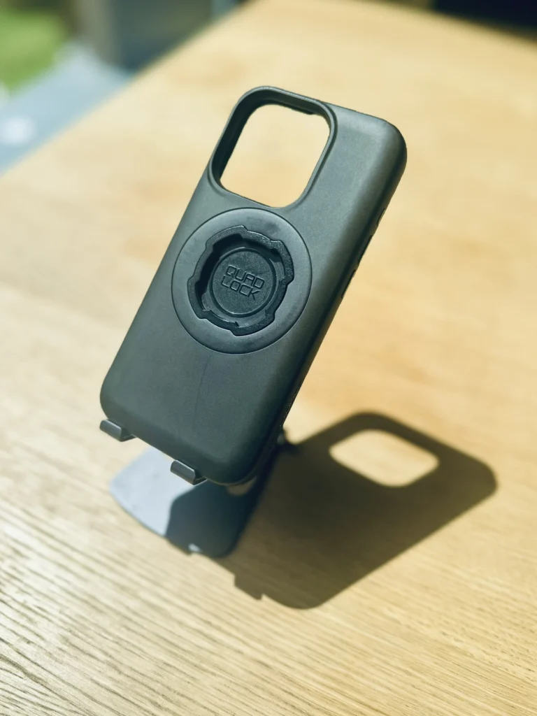 Quad Lock motorcycle phone case for iPhone standing on a wooden table