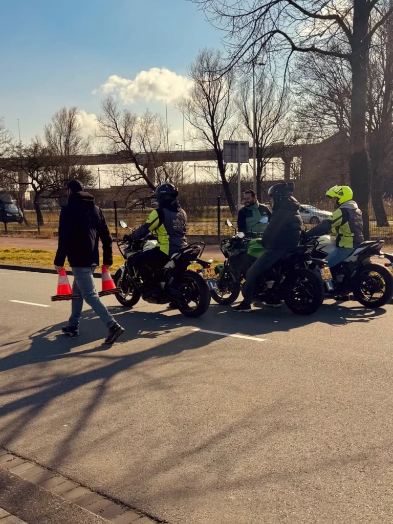 Learner motorcyclists lined up while an instructor sets out traffic cones