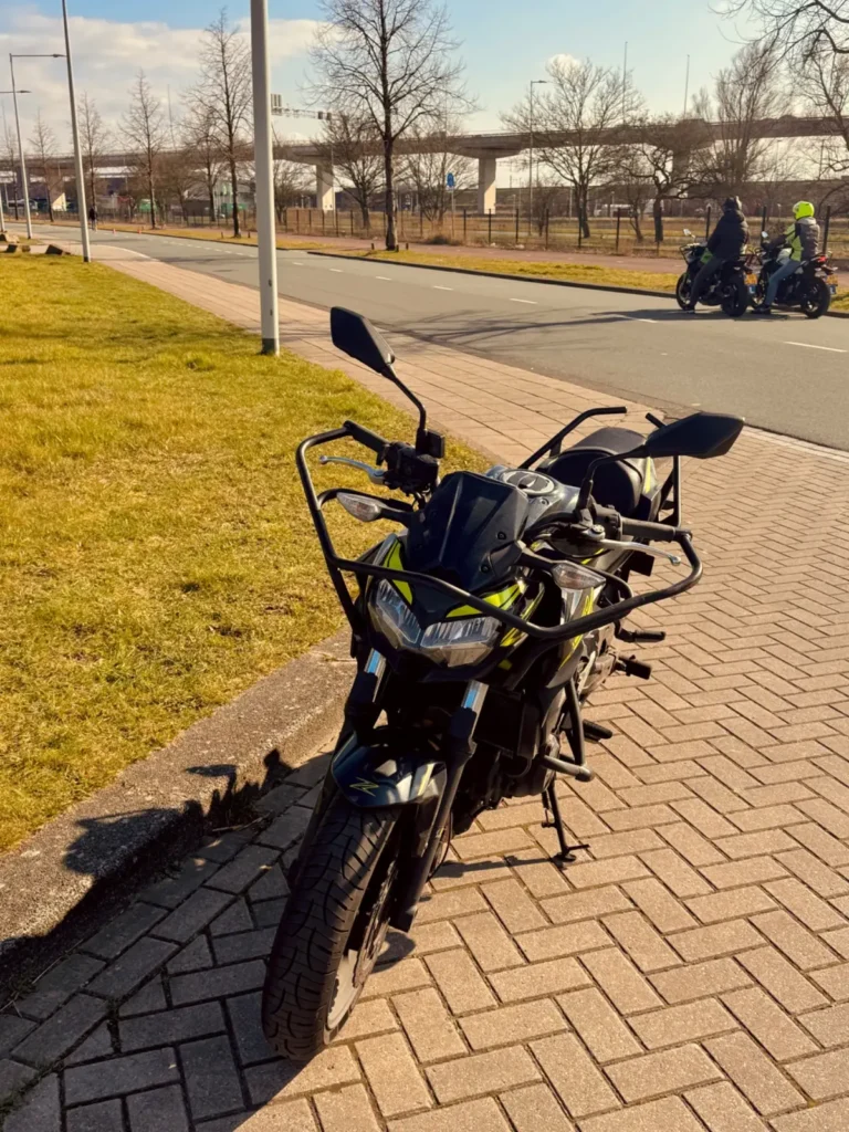 Parked training motorcycle beside the road with learner riders in the background