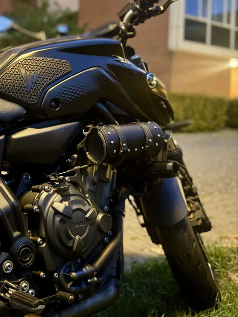 Close-up of a small black leather tool bag attached beside the Yamaha MT-07 engine