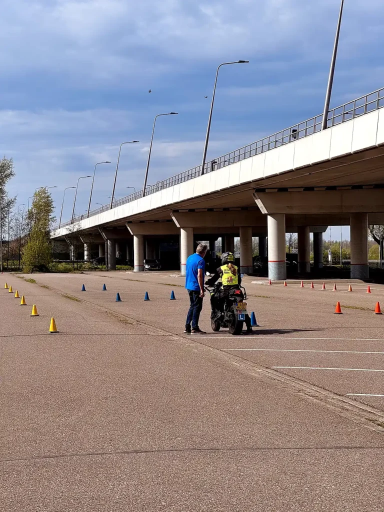 Instructor guiding a beginner motorcycle rider through a cone balance drill