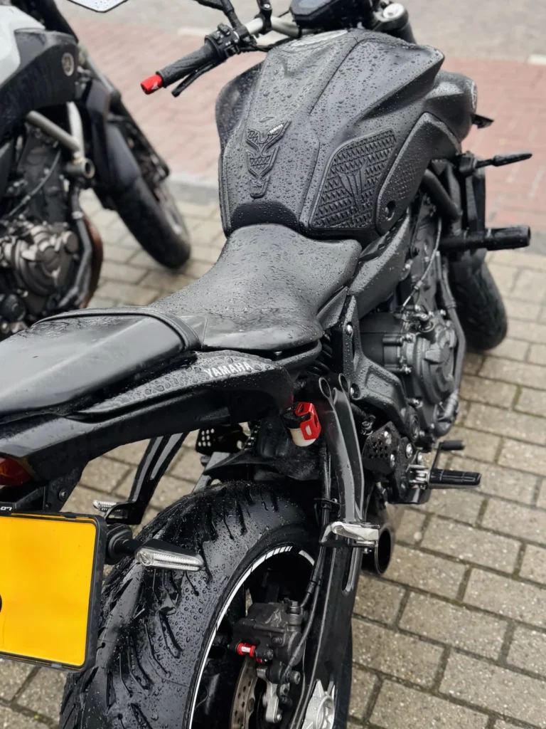 Motorcycle parked by roadside on a rainy day in urban street