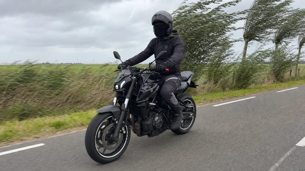 Motorcyclist riding on an exposed road in strong wind