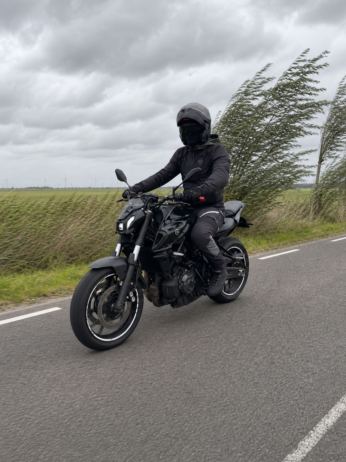 Motorcyclist riding on an exposed road in strong wind