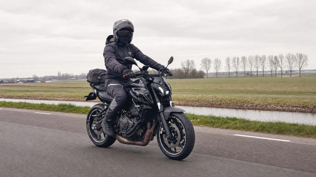 Motorcyclist riding a black Yamaha MT-07 on a quiet open road during a long ride