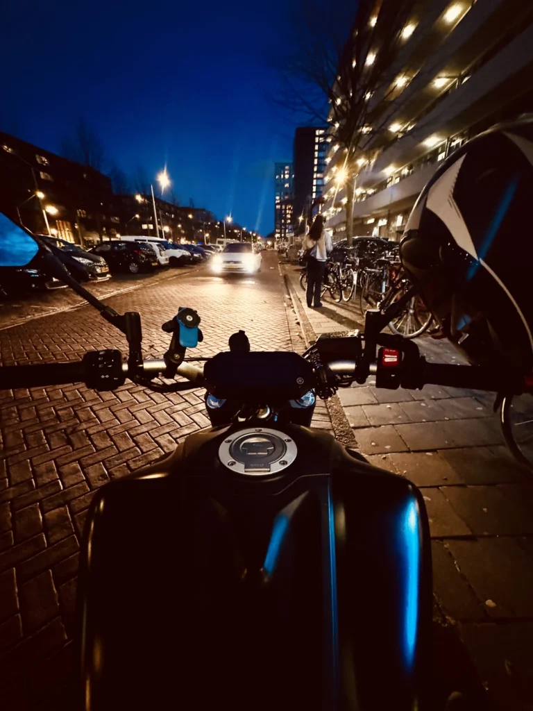 Rider view over motorcycle cockpit on a lit city street at night