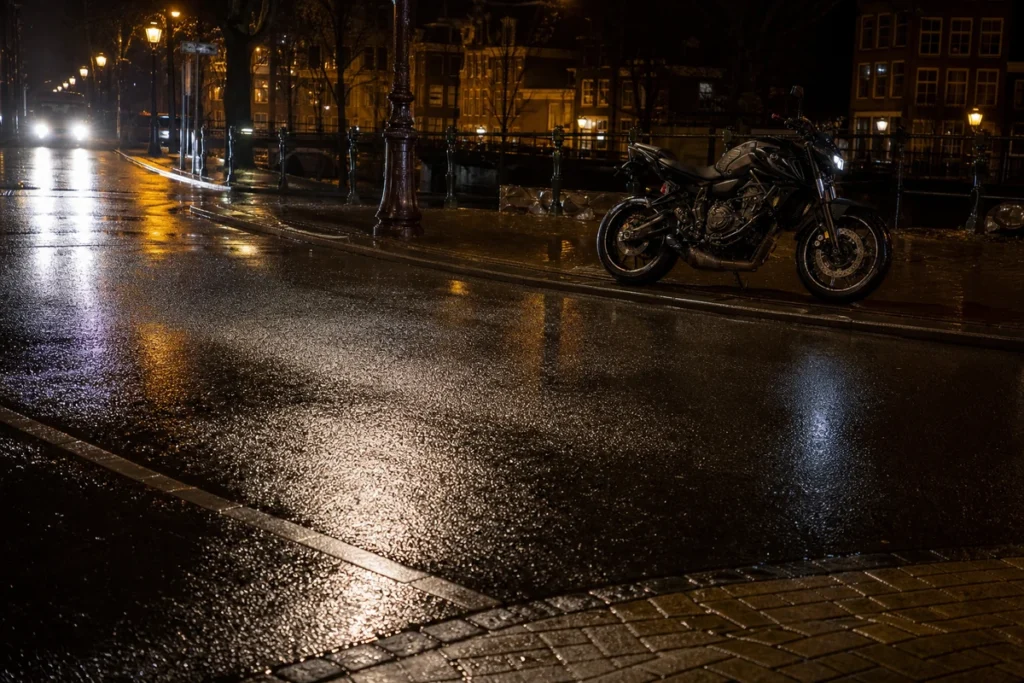 Headlight reflections on a wet road during a motorcycle night ride