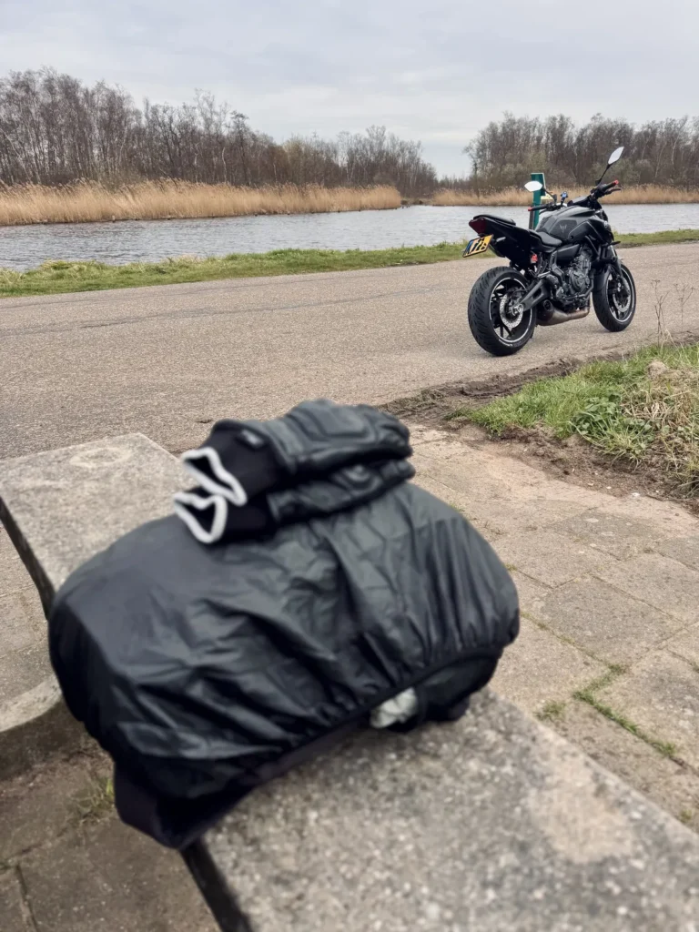Motorcycle gloves resting in the foreground with a Yamaha MT-07 parked beside the water