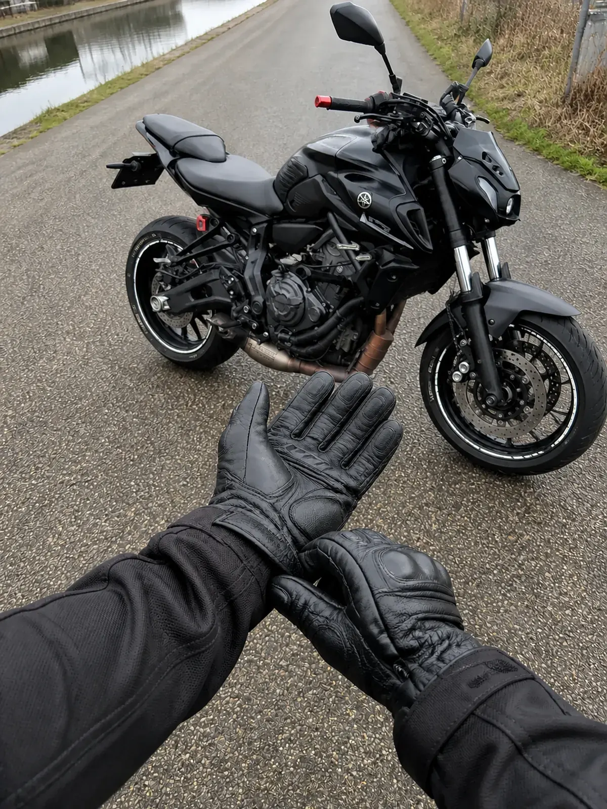 Standing rider POV tightening black motorcycle gloves before getting on a parked Yamaha MT-07
